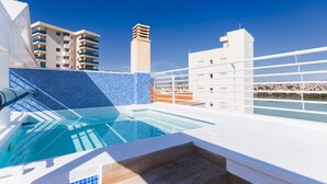 A rooftop pool with a clear view of the cityscape, including high-rise buildings and a distinctive tower.