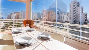 A dining table set with plates, glasses, and cutlery in a room with large windows overlooking a cityscape.