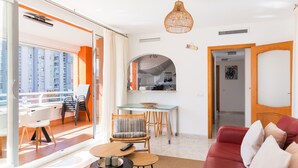 A modern living room with a balcony, a dining area, and a red sofa.