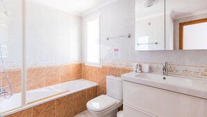 A modern bathroom with a bathtub, toilet, and sink.