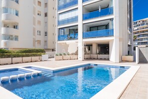 Un bâtiment moderne doté d’une piscine, de nombreux balcons et offrant une vue sur un ciel dégagé.
