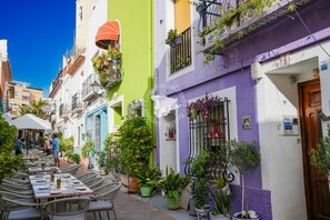 Une rue étroite avec des tables en terrasse et des plantes en pot.