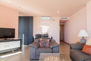 Un salon moderne avec un canapé, un téléviseur et une table basse.