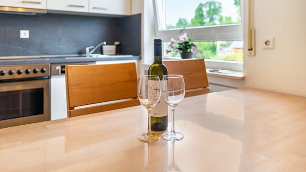 A kitchen with a wine bottle and two glasses on the counter.