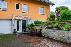 A house with a garage, a covered entrance, and a garden with various plants.