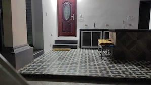 A room with a patterned floor, a red door, a small table with a cushion, and a patterned wall. - Mimos' le Café (Machala)