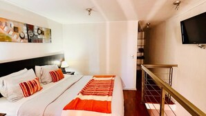 Un dormitorio con una cama, un cuadro, un televisor y una escalera.