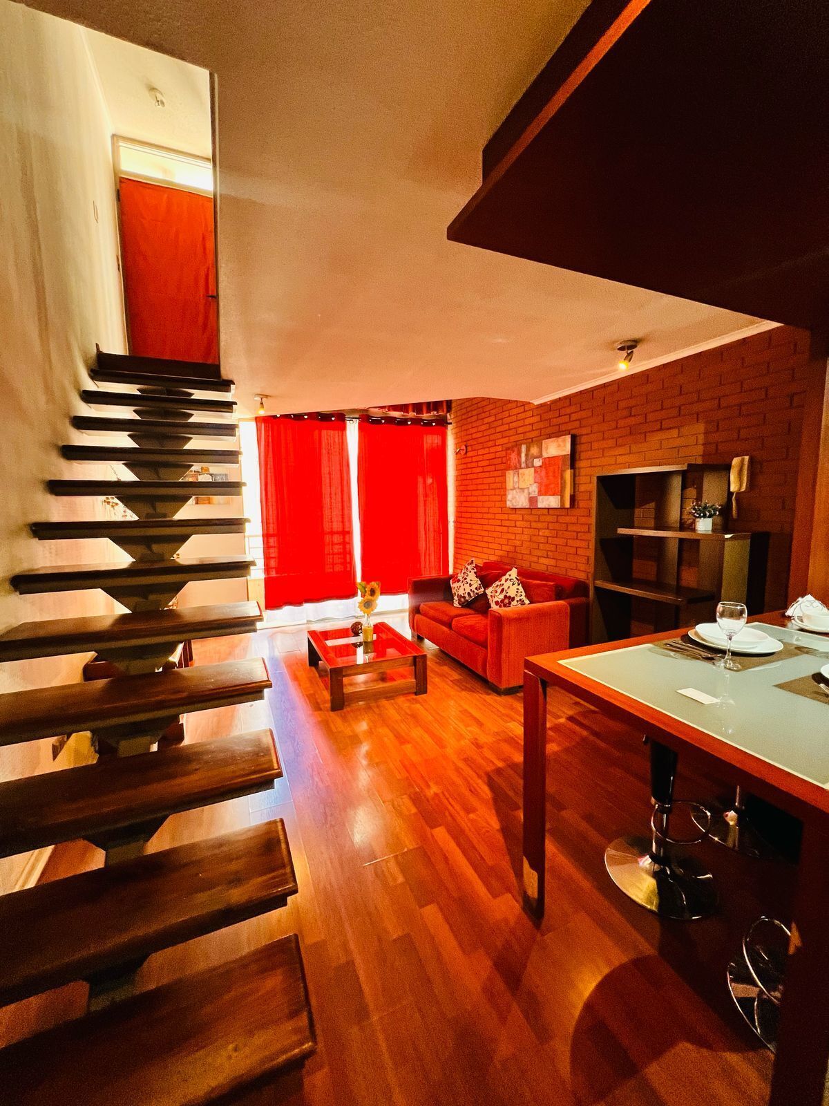 Un interior moderno con una escalera de madera, un sofá rojo y un comedor.