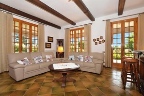 A living room with a sofa, a round table, a lamp, and a wooden stool.