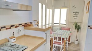 A kitchen with a wooden countertop, a dining area with a table and chairs, a potted plant, and a wall with a motivational quote. - Apartment Angel in San Fernando (San Fernando)
