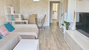A modern living room with a sofa, a coffee table, a TV, and a dining area with chairs and a table. - Apartment Angel in San Fernando (San Fernando)