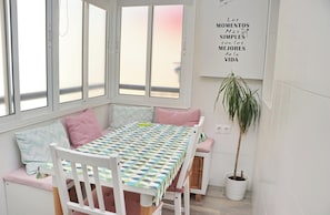 A cozy room with a dining table, chairs, a bench, and a potted plant.