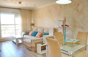 A modern bedroom with a bed, bedside table, and a glass dining table with chairs.