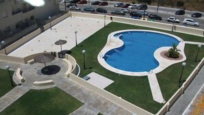 An aerial view of a parking lot with a swimming pool, a landscaped area with a circular seating arrangement, and a building in the background. - Apartment Angel in San Fernando (San Fernando)