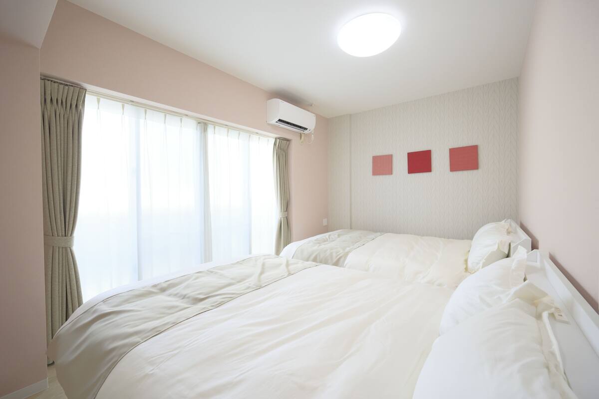 Une chambre d’hôtel avec un grand lit, un appareil de climatisation et une fenêtre avec des rideaux.