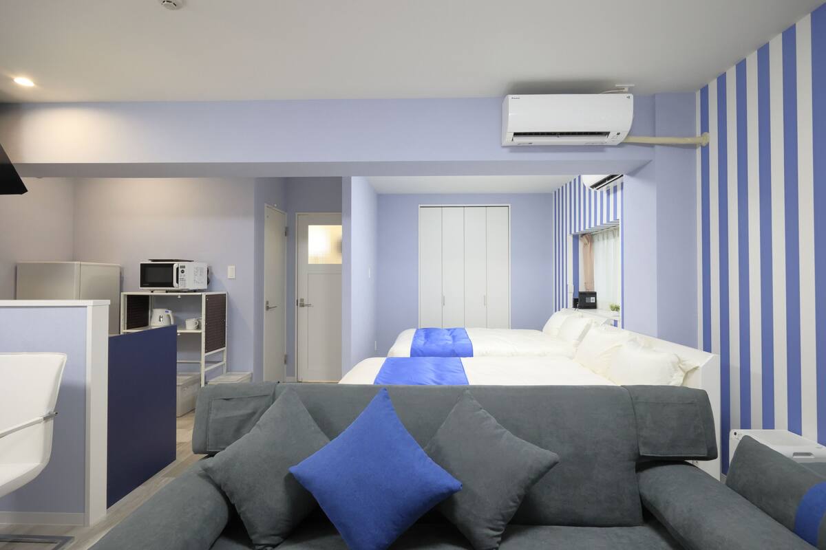 Une chambre d’hôtel équipée d’un lit, d’un canapé gris, d’un four à micro-ondes et d’un appareil de climatisation.