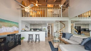 A spacious living area with a high ceiling, a kitchen, and a dining area. - OceanFront 2BD with Ocean Views and AC - Hoyochi Nikko 208 (Lahaina)