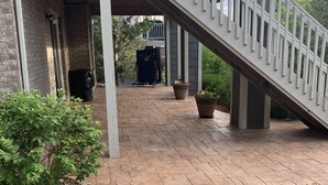 Un espace extérieur abrité, doté d’un chemin en pierre, de plantes en pot et d’un escalier menant à un bâtiment.