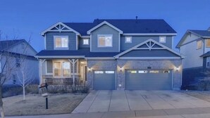 Une maison à deux étages avec un garage, un porche à l’avant et une pelouse bien entretenue.