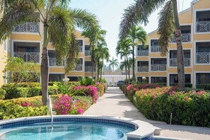 A resort with a pool, palm trees, and a pathway leading to the buildings.