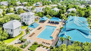 Vue aérienne d’un quartier résidentiel avec une grande piscine entourée de maisons aux toits bleus.