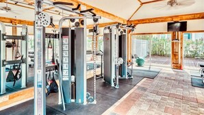 Une salle de sport équipée de matériel de musculation, dotée d’un ventilateur de plafond et offrant une vue sur l’extérieur.