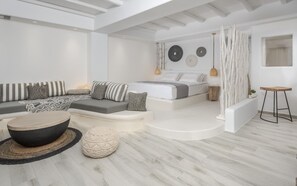 A modern, minimalist bedroom with a sofa, bed, and ottoman. - Iliada Suites Adults Only (Naxos)