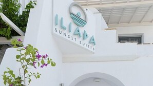 A white building with a sign reading "ILIANA SUNSET SUITES". - Iliada Suites Adults Only (Naxos)