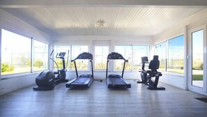 Un gimnasio interior amplio con tres cintas de correr, una bicicleta estática y una máquina de remo.