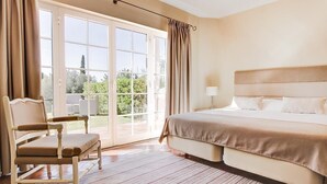 Un dormitorio con una cama grande, una silla y vistas al exterior a través de un ventanal.