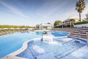 A swimming pool with a water feature, a covered seating area, and a building with a white facade. - Cegonha Country Club (Loulé)