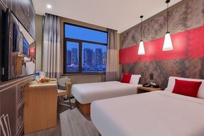 A hotel room with two beds, a desk, a chair, and a TV.