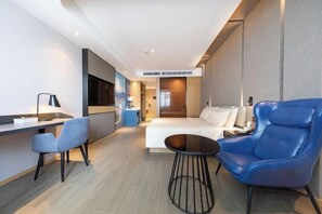 Una habitación de hotel moderna con cama, escritorio, silla y una pequeña mesa.