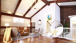 Ein geräumiges Wohnzimmer mit Holzböden, einem Hängekorbsessel, einer Couch und einer Treppe, die in ein Obergeschoss führt.