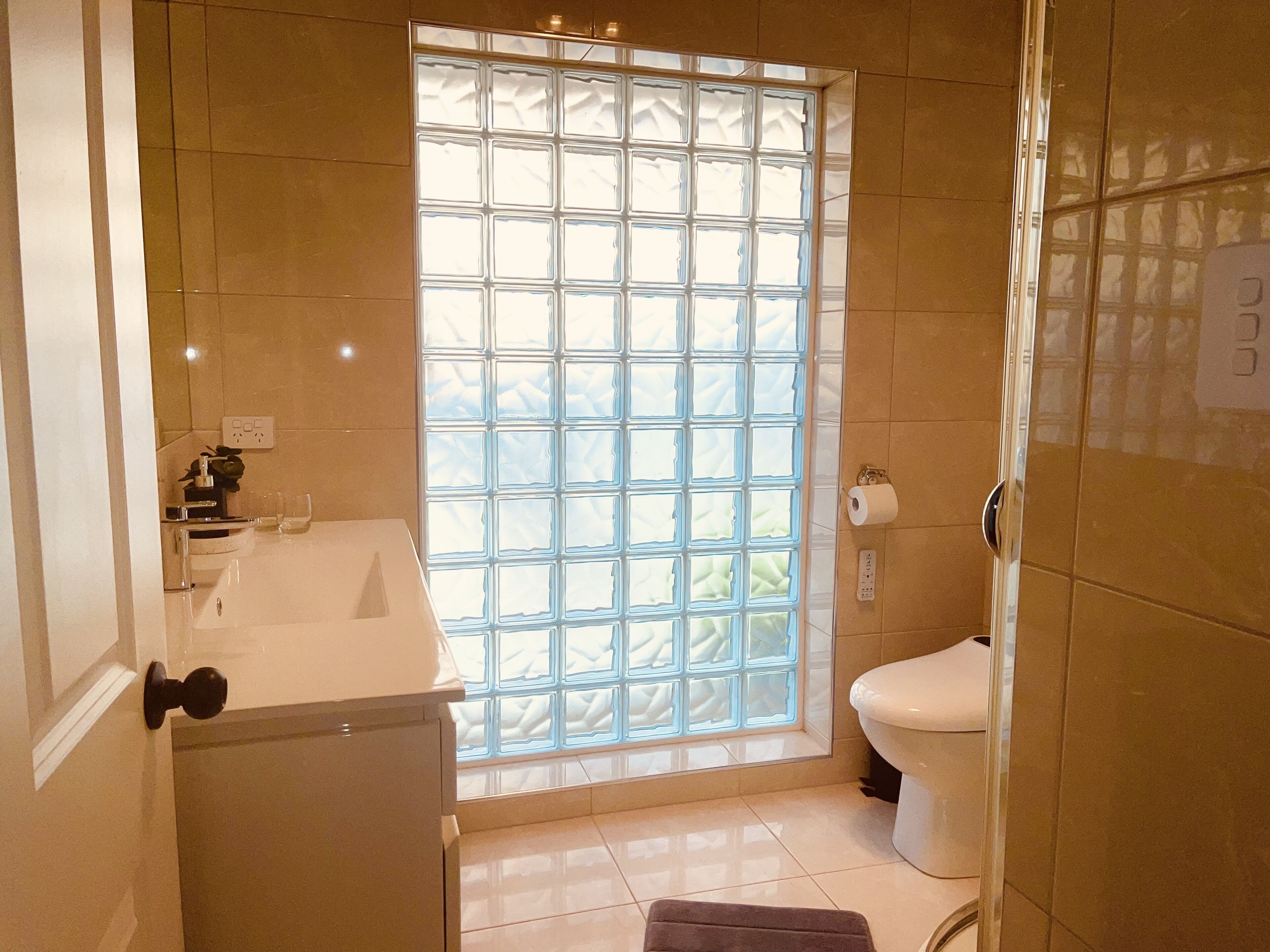 A bathroom with a large window, a sink, and a toilet.