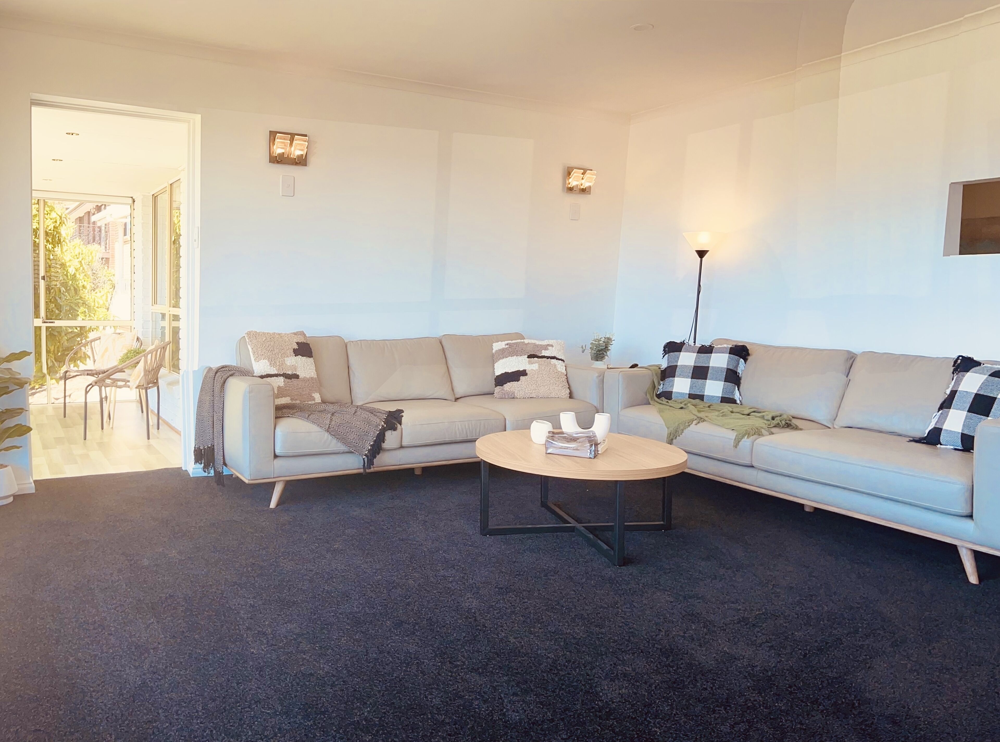 A modern living room with a beige sofa, a round coffee table, and a dining area with chairs and a table.