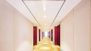 A hotel corridor with a long, narrow layout, red curtains on the walls, and a shiny, reflective floor. - IU Hotel (Yanshi Baima Temple) (Luoyang)