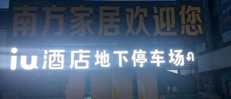 A hotel sign with Chinese characters and a parking lot with cars.