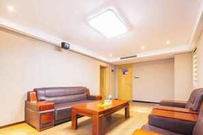 A room with a brown leather sofa, a wooden coffee table, and a massage chair. - IU Hotel (Yanshi Baima Temple) (Luoyang)