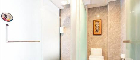Un baño moderno con cabina de ducha de vidrio, inodoro y lavamanos empotrado.