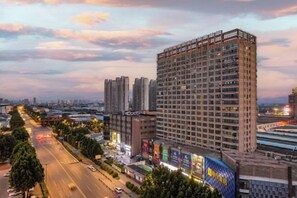 Ein Hochhaus mit mehreren Stockwerken, umgeben von einer belebten Straße mit Fahrzeugen und leuchtenden Schildern.