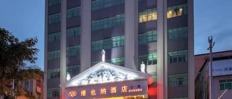 A hotel with a prominent entrance and a large building in the background.