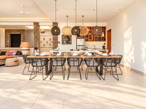 A modern dining area with a long table, black chairs, and pendant lighting. - Opulent 6 BR in Canggu, 400m to Finns Beach Haven (Canggu)
