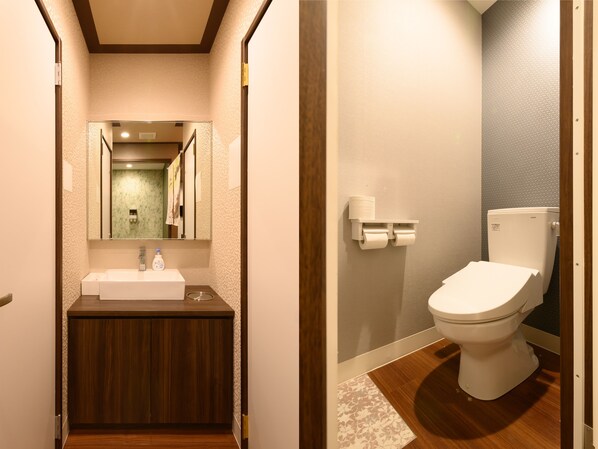 A bathroom with a wooden vanity, a mirror, and a toilet. - Tabist Capsule Inn Kasakake (Midori)