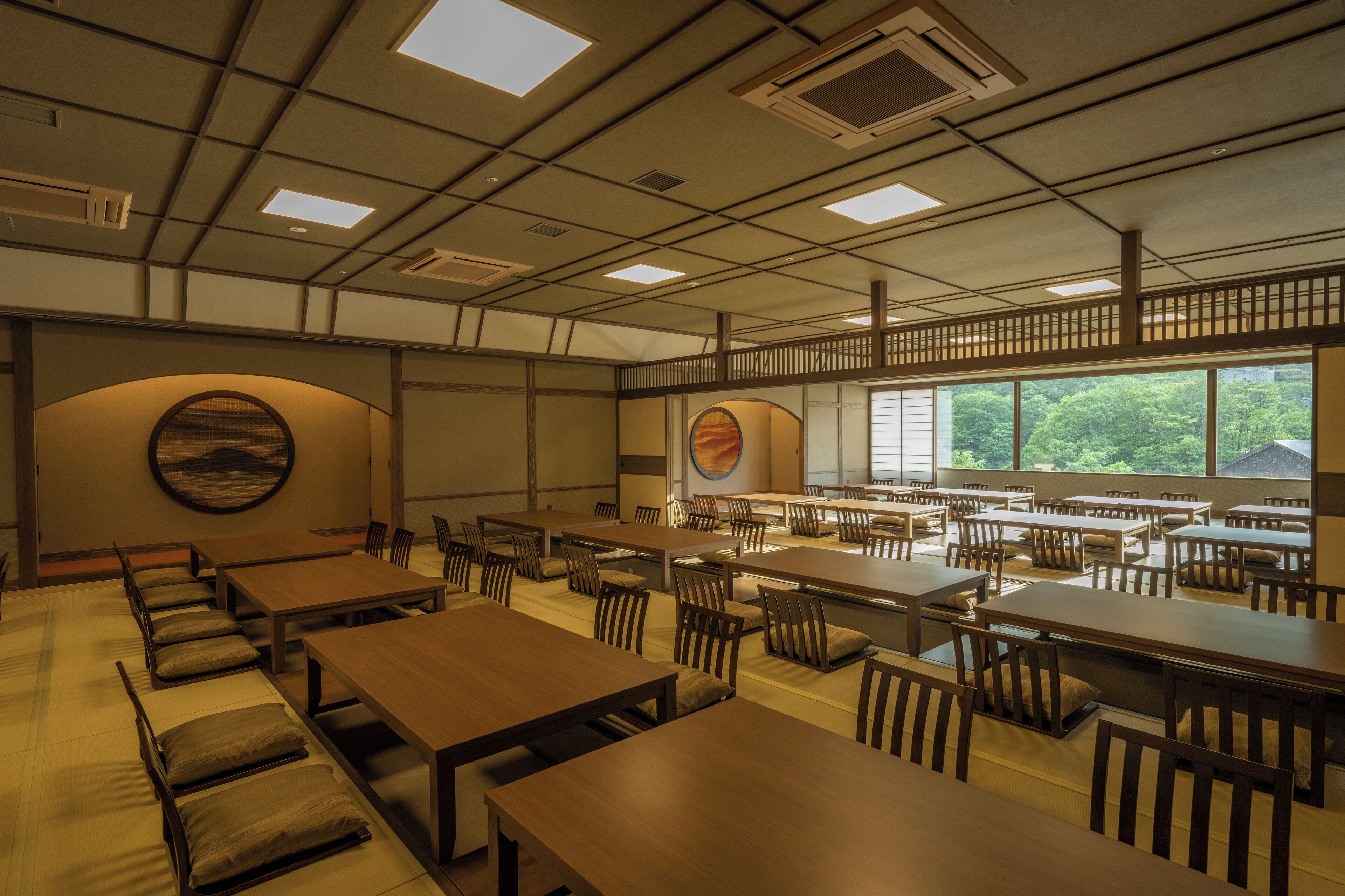 Un restaurant japonès tradicional amb terra de tatami, taules de fusta i vista a la vegetació a través de grans finestres.