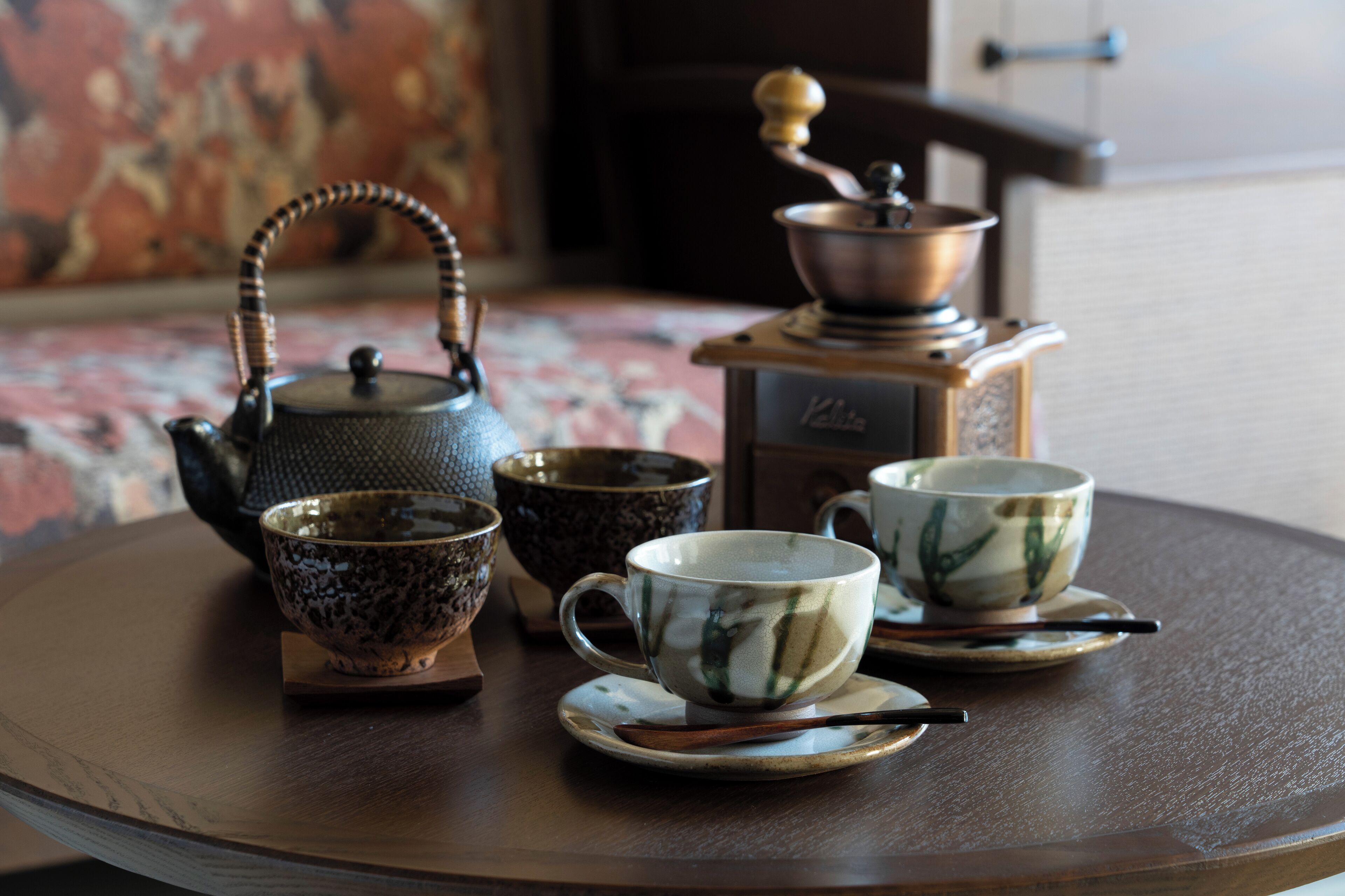 A round wooden table with a teapot, two cups, and a small bowl.