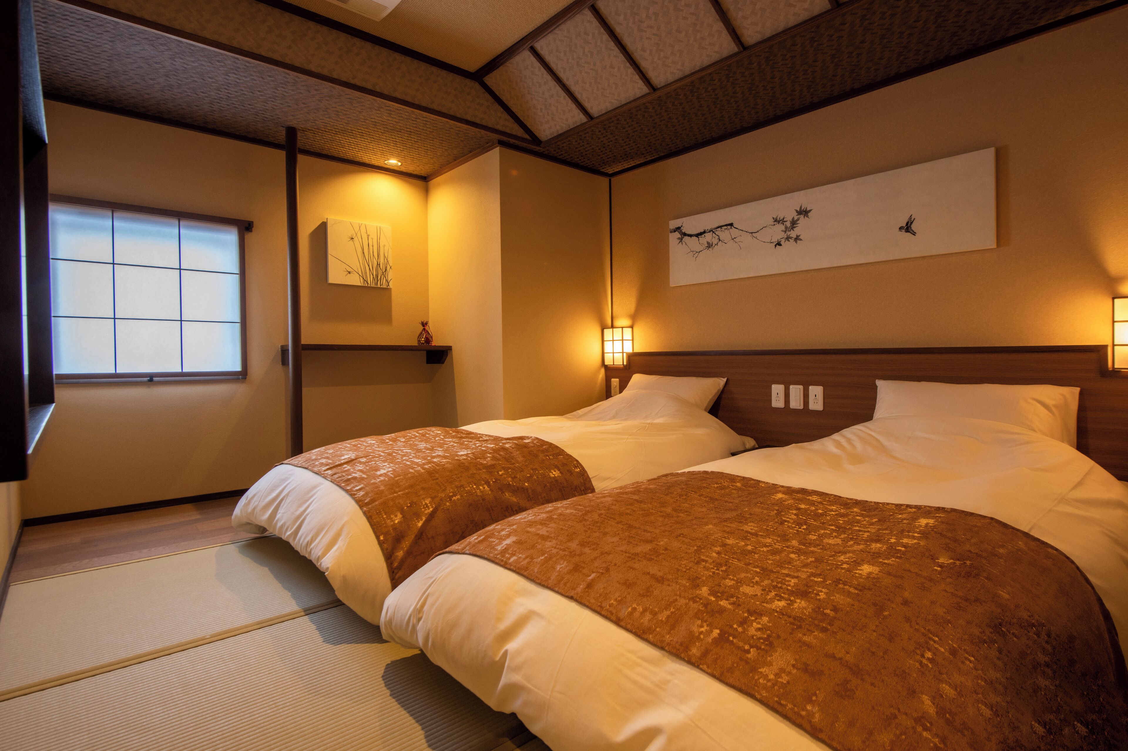 A hotel room with a large bed, a bedside table, a wall-mounted artwork, and a window with a view.