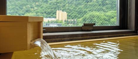 A wooden bath with a view of a mountainous landscape through a window.