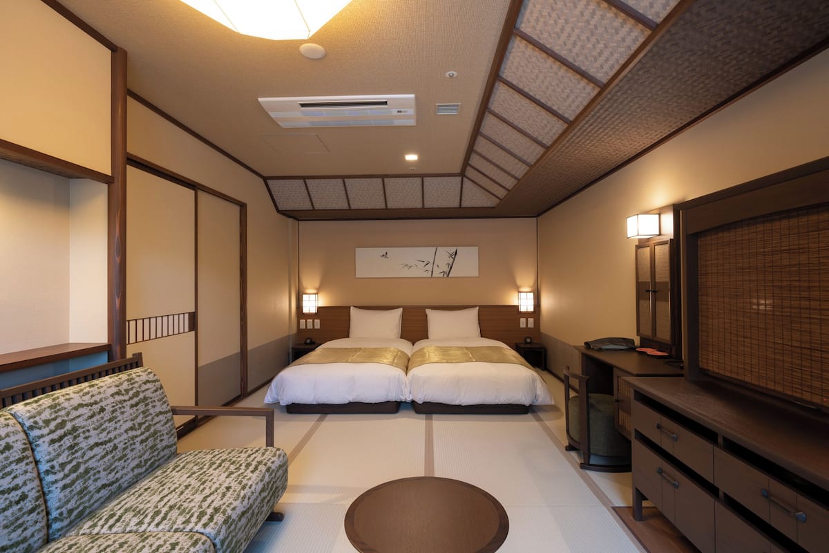 Ein Hotelzimmer mit Bett, Sofa, Fernseher und Kommode.
