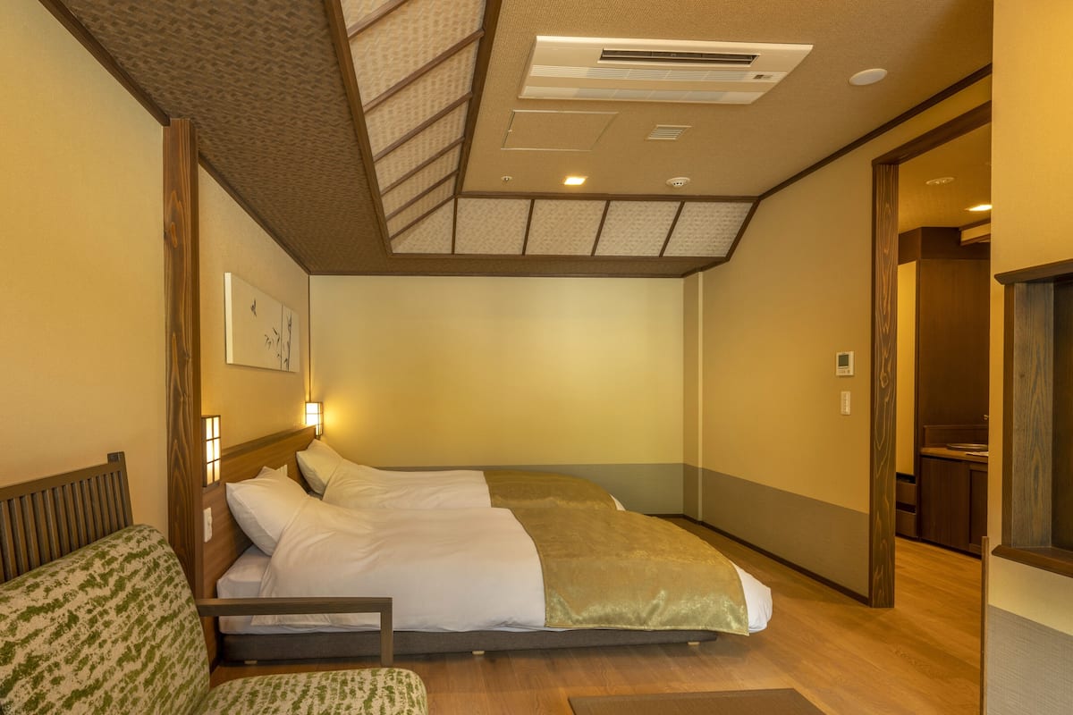 Ein Hotelzimmer mit Bett, einer Couch, einem kleinen Tisch und Holzboden.